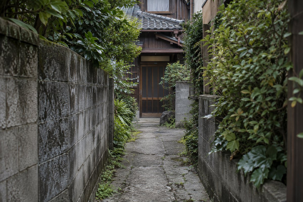 ブロック塀と生垣に挟まれた細い通路の先にある、古い木造住宅の玄関