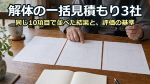3通の見積書を食卓に並べ、老眼鏡をかけた手元が見比べている