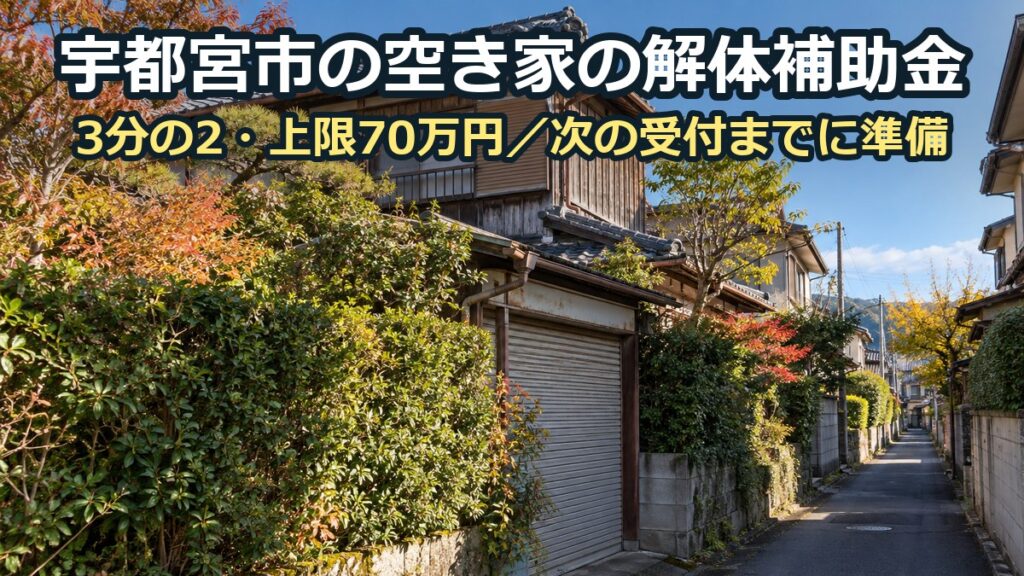 生け垣の伸びた古い木造二階建ての空き家と、その前の細い坂道。奥に住宅が続く