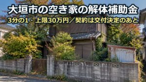 庭木が伸びて枝が屋根にかかった木造二階建ての空き家。物置とブロック塀も残っている